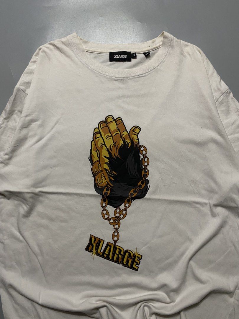 XLARGE White Praying Hands Graphic T-Shirt (Category: Tshirts & Polo Shirts ) located in Silang. Submitted by kenneth_ukays (Listing ID 1463343227, Image 1). Description: - XLARGE White T-Shirt - Size: XL - Features a cool praying hands graphic - Includes a gold chain detail - XLARGE logo present - Made in China - Ideal for casual wear.