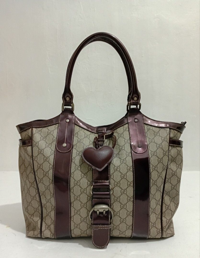 Vtg GUCCI STRUCTURED PUNCH TOTE BAG (Category: Luxury Bags & Wallets) located in Navotas City. Submitted by riyuwi (Listing ID 1463484902, Image 1). Description: PreOwned Lightly uSed Authentic Y2k Gucci STRUCTURED LARGE PUNCH TOTE - Classic GG monogram canvas - Shiny dark brown patent leather trim and handles -Coded - Cute heart-shaped charm and buckle detail - Interior with patterned lining and zippered pockets - Spacious design for everyday us