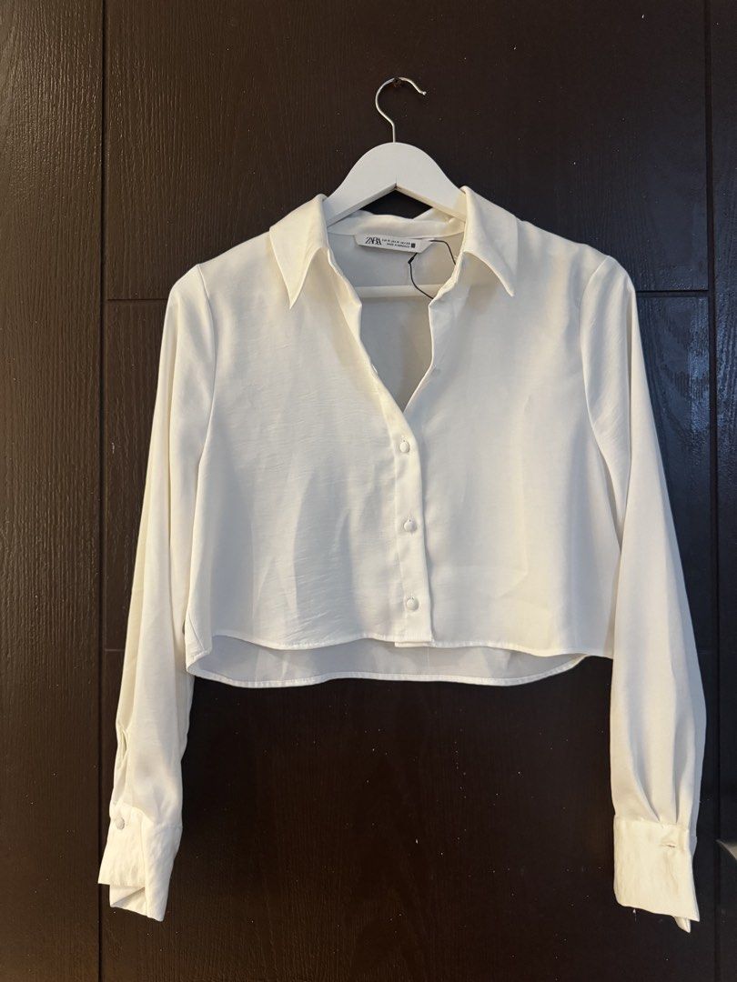Zara White Cropped Button-Up Shirt (Category: Shirts) located in Paranaque City. Submitted by keyrends (Listing ID 1463418798, Image 1). Description: - White cropped shirt from Zara - Long sleeves with button cuffs - Button-up front closure - Estimated size: Medium - Perfect for dressing up or down - Easy to pair with high-waisted bottoms.