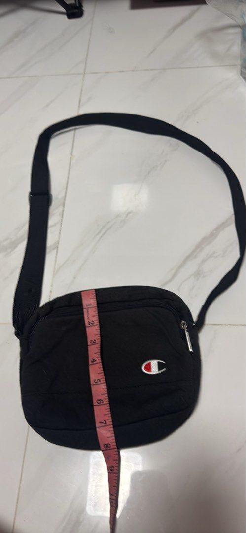 2027 Champion Black Crossbody Bag (Category: Cross-body Bags) located in Silang. Submitted by sari2bilina (Listing ID 1463667725, Image 1). Description: - Authentic Champion crossbody bag - Ideal for everyday essentials - Main zippered compartment for secure storage - Inner pocket for organization - Adjustable strap for a comfortable fit - Compact size: approximately 8" wide, 5" tall, and 2" deep.