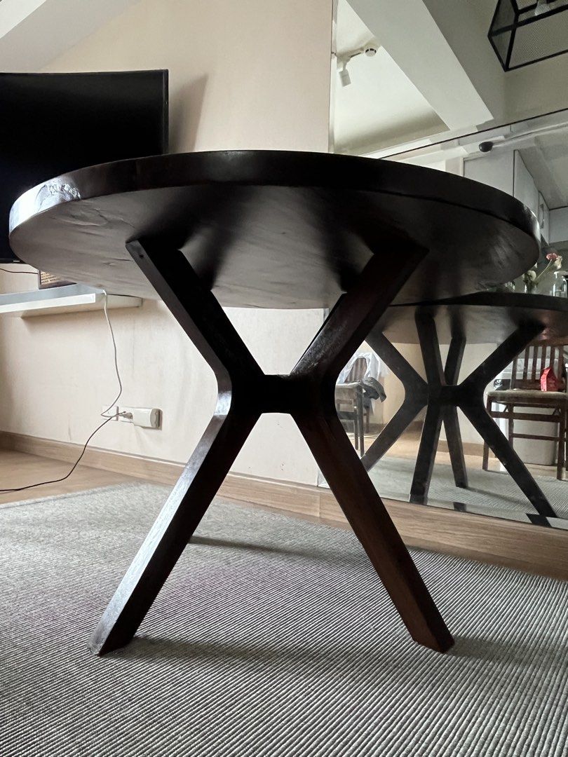 Acacia Solid Wood Round Dining Table with Unique Base (Category: Tables & Sets) located in Manila. Submitted by lg1023 (Listing ID 1463704509, Image 3). Description: - Dark wood round coffee table - Unique criss-cross base design - Shows some signs of wear, including a visible crack on the tabletop edge - Still sturdy and stylish - Dimensions: Approximately 110 cm.