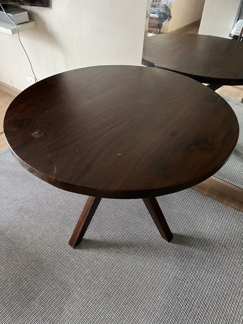 Acacia Solid Wood Round Dining Table with Unique Base (Category: Tables & Sets) located in Manila. Submitted by lg1023 (Listing ID 1463704509, Image 1). Description: - Dark wood round coffee table - Unique criss-cross base design - Shows some signs of wear, including a visible crack on the tabletop edge - Still sturdy and stylish - Dimensions: Approximately 110 cm.