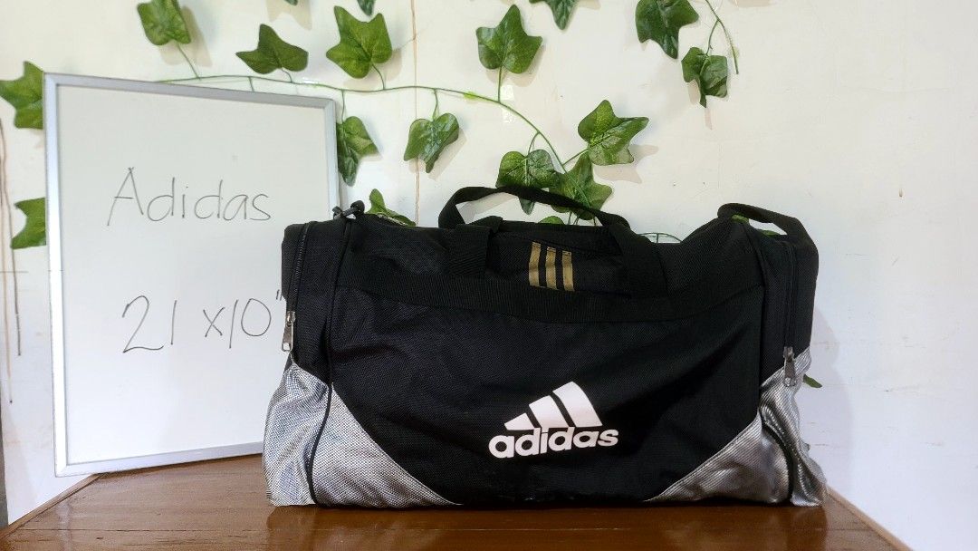 Adidas Duffel Bag Black Gold (Category: Sling Bags) located in Baguio. Submitted by phoeberose33384 (Listing ID 1463739192, Image 1). Description: - Black Adidas duffel bag - Gold accents - Main compartment and side pockets - Zippers in good working condition - Sturdy handles - Ideal for gym or travel - Approximately 21 inches long.