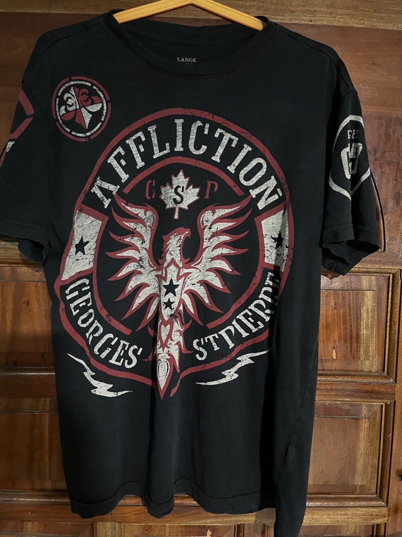 Affliction Georges St-Pierre "Rush" T-Shirt (Category: Tshirts & Polo Shirts ) located in Cebu City. Submitted by rockall24455 (Listing ID 1463741664, Image 1). Description: - Black Affliction T-Shirt - Georges St-Pierre "Rush" graphic on front and back - Size: Large 21.5x28 dimes - Material: 100% Cotton - Made in USA - Care Instructions: Machine wash cold, do not bleach, tumble dry low, do not iron - Ideal for MMA and UFC enthusiasts.