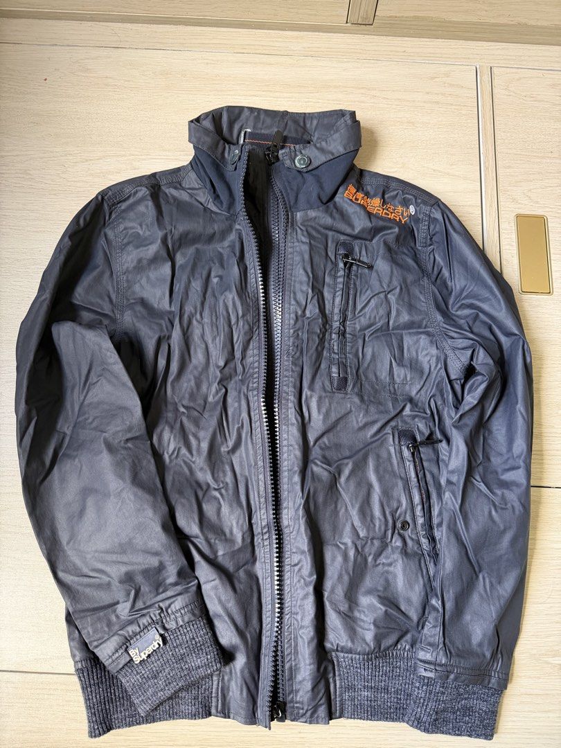 Authentic Superdry Original Moody Bomber Jacket Dark Grey Size S (Category: Coats, Jackets and Outerwear) located in Pasig City. Submitted by chic.crate (Listing ID 1463564967, Image 1). Description: Superdry Original Moody Bomber jacket in dark grey. Features a zip-up front with button closure at the collar. Two zip pockets on the front and one on the chest. Ribbed cuffs and hem. Orange Superdry branding on the chest and back. Inner lining is de
