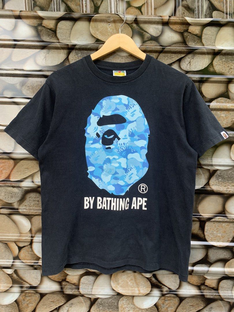 BAPE Blue Camo Ape Head T-Shirt (Category: Tshirts & Polo Shirts ) located in Aloran. Submitted by chester78864 (Listing ID 1463659109, Image 1). Description: - Authentic Black BAPE T-Shirt - Iconic Blue Camo Ape Head Graphic - "BY BATHING APE" text detail - Size: Medium (M) - Small BAPE tag on sleeve - Essential piece for any streetwear enthusiast.