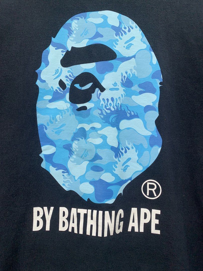 BAPE Blue Camo Ape Head T-Shirt (Category: Tshirts & Polo Shirts ) located in Aloran. Submitted by chester78864 (Listing ID 1463659109, Image 2). Description: - Authentic Black BAPE T-Shirt - Iconic Blue Camo Ape Head Graphic - "BY BATHING APE" text detail - Size: Medium (M) - Small BAPE tag on sleeve - Essential piece for any streetwear enthusiast.