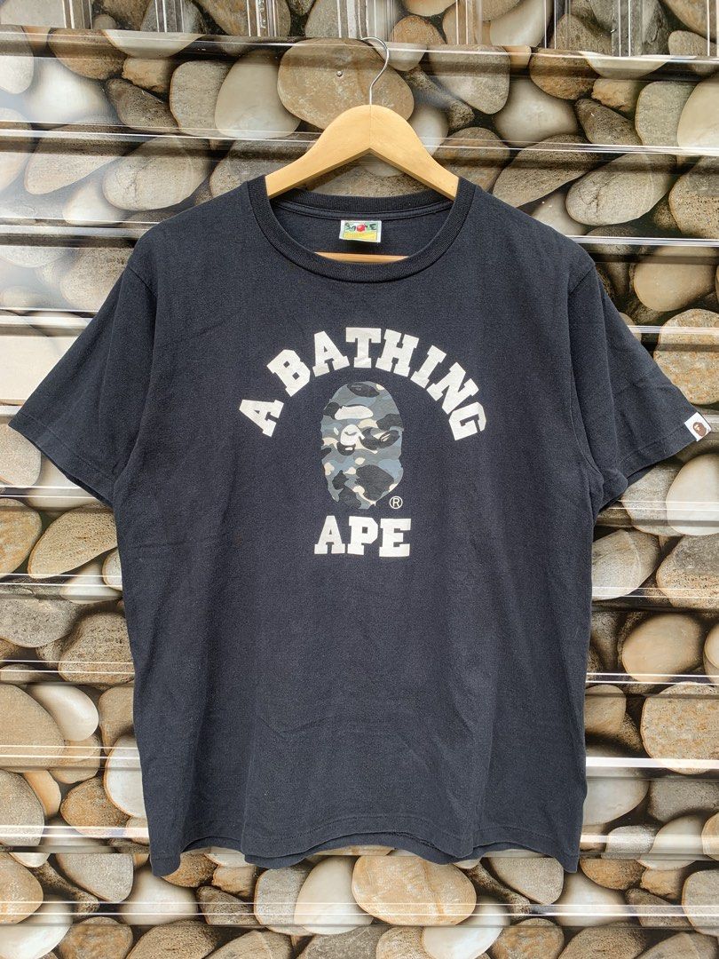 Bape college tee GITD (Category: Tshirts & Polo Shirts ) located in Aloran. Submitted by chester78864 (Listing ID 1463658078, Image 1). Description: - Classic black A Bathing Ape (BAPE) t-shirt - Features iconic camo ape head graphic on the front - BAPE logo arched above, 'APE' below the graphic - Small ape head tag detail on sleeve and hem - Made from 100% comfortable cotton - Ideal for any streetwear enthusiast.