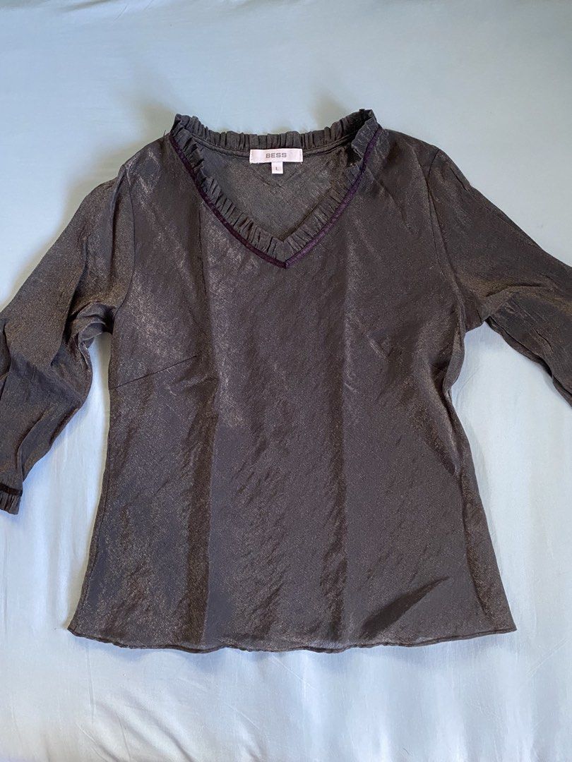 Bess Metallic Grey Ruffled V-Neck Top (Category: Sleeveless) located in Manila. Submitted by heyheyruok (Listing ID 1463611870, Image 1). Description: - Brand: BESS - Color: Dark Grey - Size: L - Neckline: Ruffled V-neck with dark trim - Sleeves: Long sleeves with ruffled cuffs and dark trim - Fabric: Subtle sheen and texture - Occasion: Suitable for casual or slightly dressier events - Much prettier in person! - Not stretchable - Perfect for off