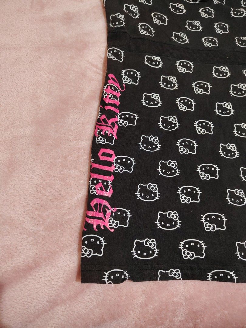 Black Hello Kitty All Over Print Babydoll Top (Category: Sleeveless) located in Villasis. Submitted by trip_thrift15 (Listing ID 1463666834, Image 2). Description: - Adorable black tank top with an all-over white Kitty print. - Features a vibrant hot pink ' Kitty' graphic down the side. - Comfortable spaghetti straps for a relaxed fit. - Made from soft, comfortable fabric. - Officially licensed by Sanrio and Blues Clothing. - Ideal for casual out