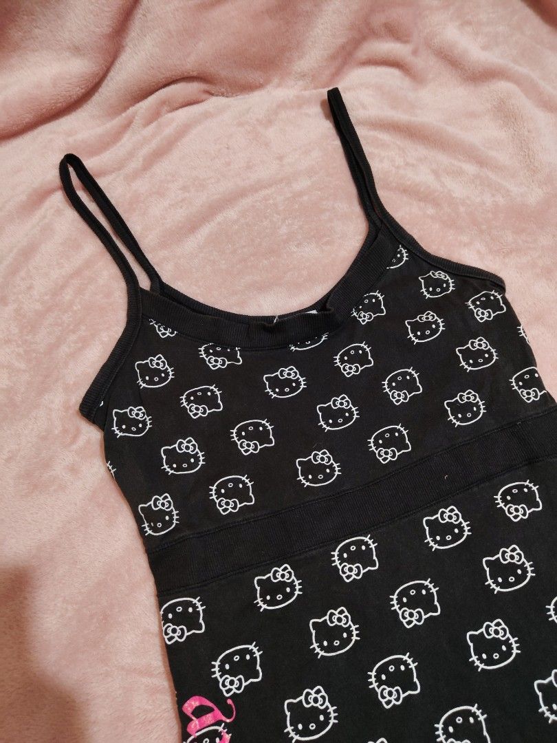 Black Hello Kitty All Over Print Babydoll Top (Category: Sleeveless) located in Villasis. Submitted by trip_thrift15 (Listing ID 1463666834, Image 3). Description: - Adorable black tank top with an all-over white Kitty print. - Features a vibrant hot pink ' Kitty' graphic down the side. - Comfortable spaghetti straps for a relaxed fit. - Made from soft, comfortable fabric. - Officially licensed by Sanrio and Blues Clothing. - Ideal for casual out