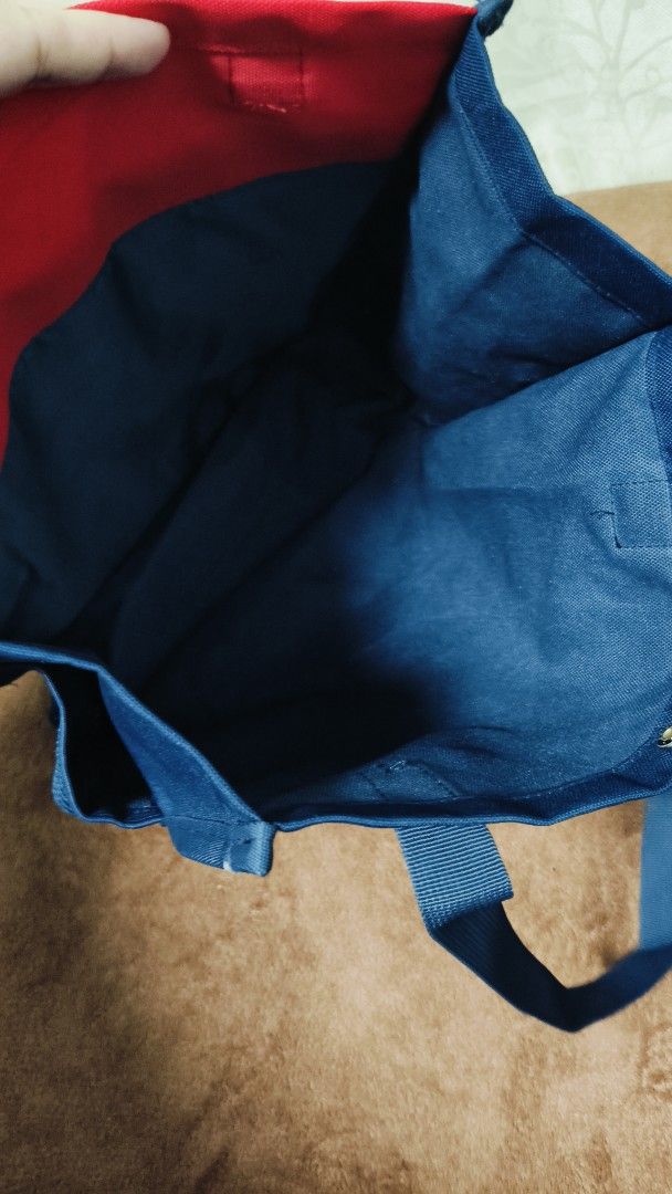 Blue and Red Book Tote (Category: Tote Bags) located in Manila. Submitted by serenitycarlylle (Listing ID 1463725675, Image 3). Description: - Stylish navy blue tote bag with eye-catching red accents. - Features a unique, fun pattern on the front pocket. - Convenient side mesh pockets for extra storage. - Spacious interior lined with vibrant red. - Durable, sturdy handles for comfortable carrying. - Ideal for everyday use, errands, or carrying yo