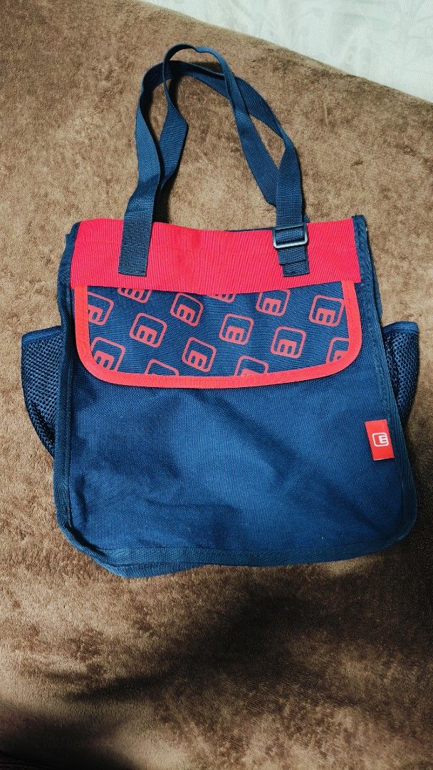 Blue and Red Book Tote (Category: Tote Bags) located in Manila. Submitted by serenitycarlylle (Listing ID 1463725675, Image 1). Description: - Stylish navy blue tote bag with eye-catching red accents. - Features a unique, fun pattern on the front pocket. - Convenient side mesh pockets for extra storage. - Spacious interior lined with vibrant red. - Durable, sturdy handles for comfortable carrying. - Ideal for everyday use, errands, or carrying yo