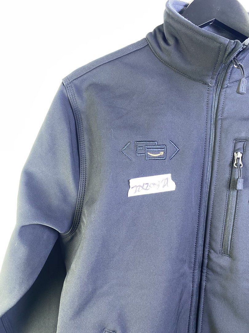 Carhartt Softshell Jacket with Amazon Logo (Category: Coats, Jackets and Outerwear) located in Manila. Submitted by declutterpromax (Listing ID 1463606144, Image 2). Description: - Dark navy Carhartt softshell jacket - Features Carhartt logo on chest - Includes embroidered Amazon logo on left chest - Multiple zippered pockets for secure storage - Versatile for work or casual wear - All zippers function smoothly.