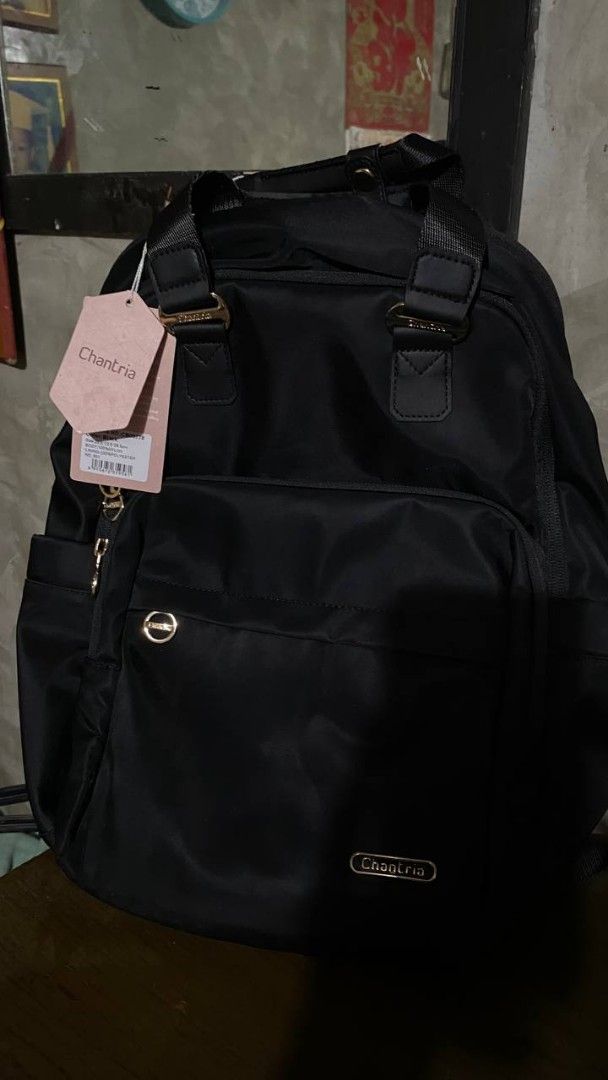 CHANTRIA BACKPACK (Category: Backpacks) located in Manila. Submitted by swifttree.c6cdcf (Listing ID 1463706779, Image 1). Description: - Brand: Chantria - Color: Black nylon exterior - Interior: Light pink lining with multiple compartments - Pockets: Front zip pocket, side pockets - Hardware: Gold details - Condition: Brand new with original tags attached ‎FS: CHANTRIA BACKPACK — ₱850 ONLY! ‎original price: ₱1,400 ‎ ‎condition: never used / in v