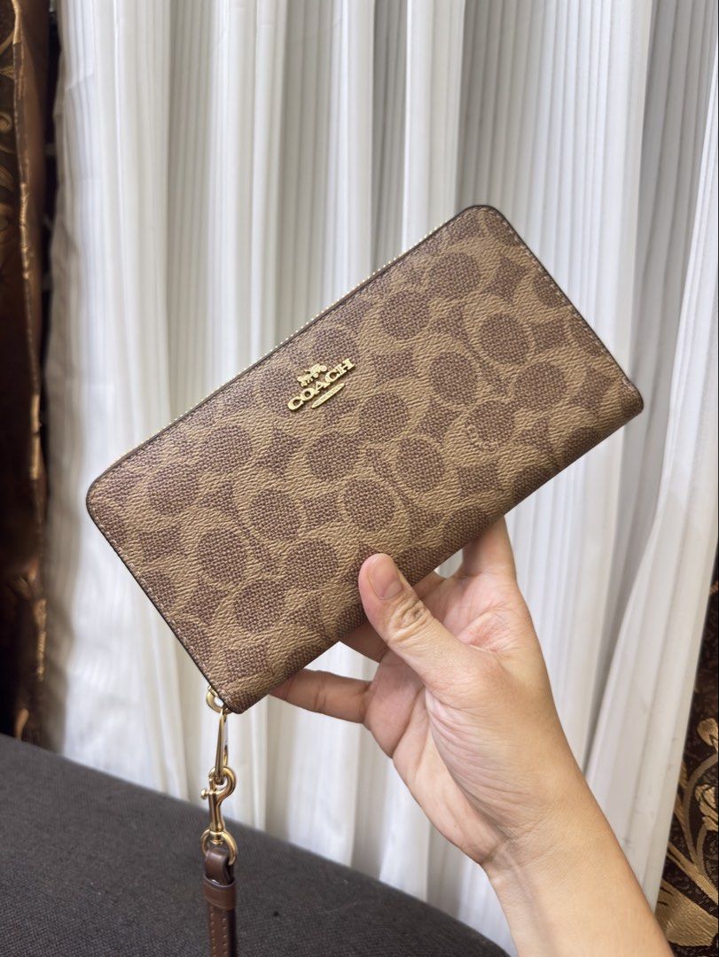 Coach Long Zip around Continental Wallet (Category: Wallets & Card holders) located in Manila. Submitted by manghobu (Listing ID 1462311917, Image 2). Description: BRANDNEW - Coach wristlet wallet in signature C pattern - Color: Brown and tan - Hardware: Gold - Closure: Zip-around - Features: Detachable wrist strap - Ample space for cards and cash - Perfect for everyday use or travel.