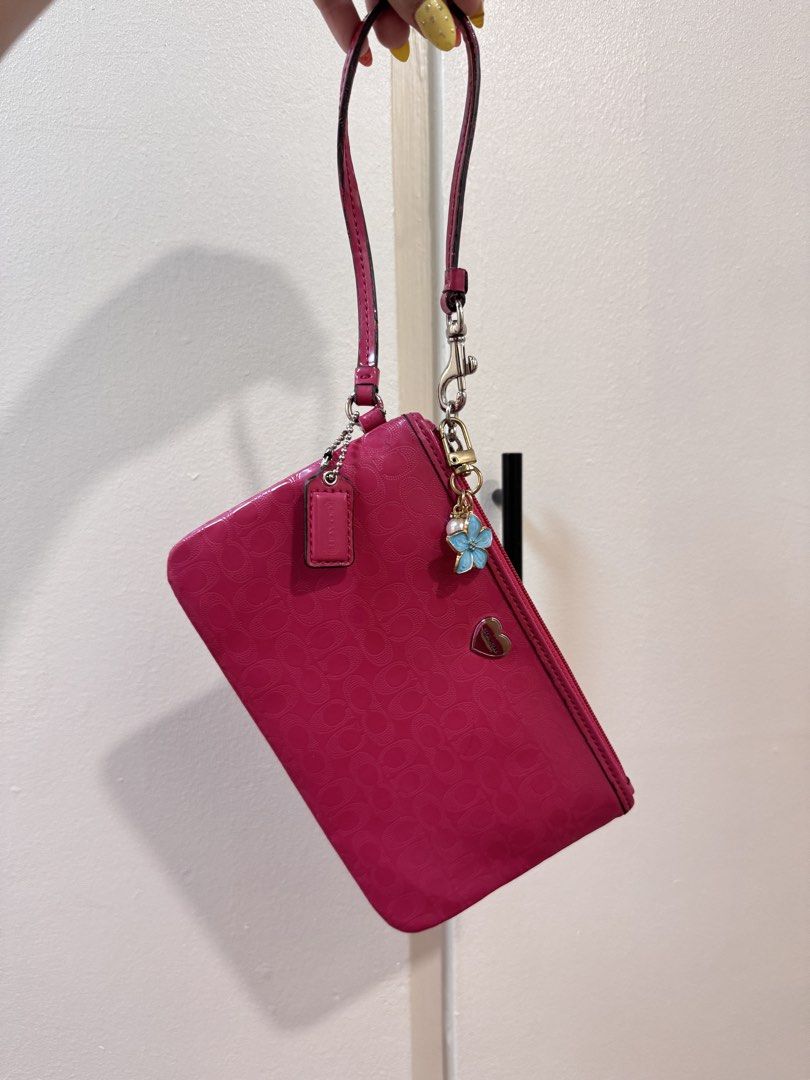 FIXED PRICE Coach Pink Wristlet Pouch (Category: Purses & Pouches) located in Manila. Submitted by livelaughlovejay (Listing ID 1463685227, Image 1). Description: - Cute pink Coach wristlet - Signature C pattern all over - Comes with a blue flower charm - Comes with a small heart charm - Zipper closure - Perfect for carrying essentials.