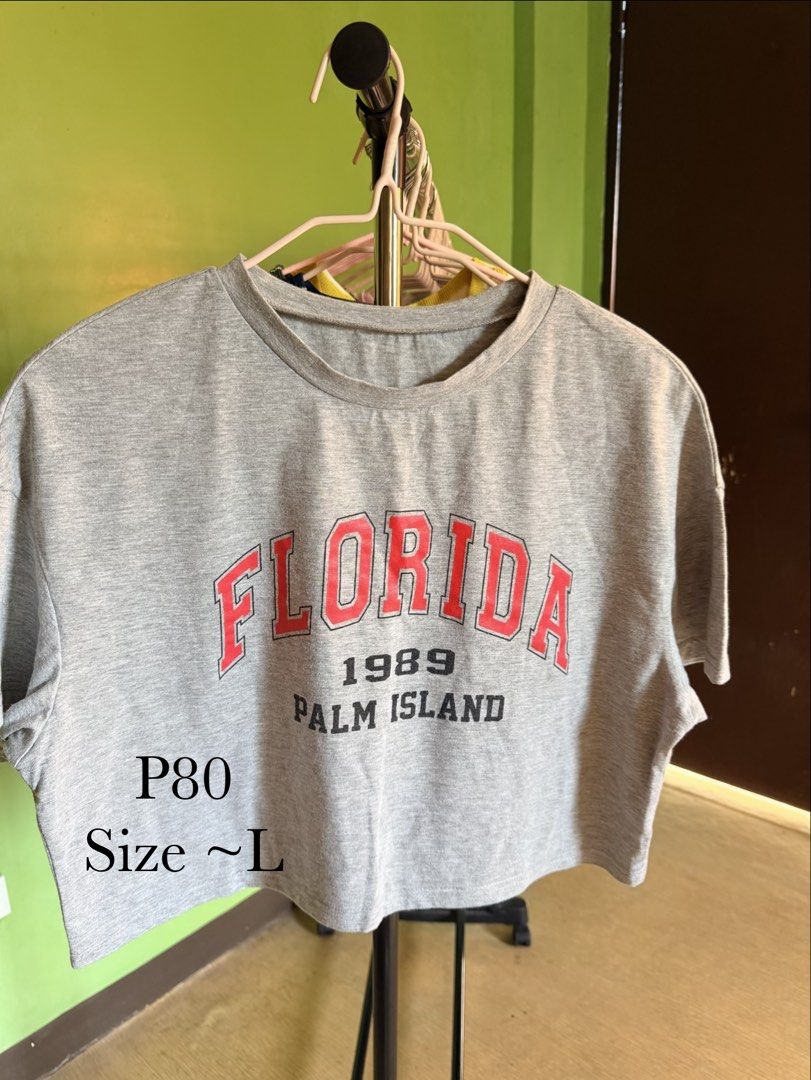 Cropped T-shirt (Category: Shirts) located in Muntinlupa City. Submitted by cocofinds023 (Listing ID 1463711630, Image 1). Description: - Grey cropped t-shirt - Features 'Florida 1989 Palm Island' graphic print - Comfortable and casual fit - Best fits around a size L - Perfect for everyday wear.