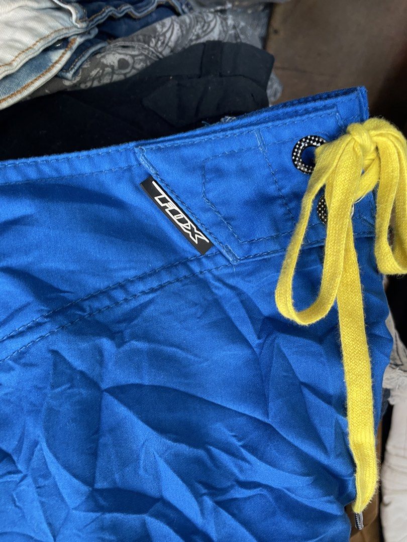 Fox Racing Blue Yellow Board Shorts (Category: Swim Trunks & Board Shorts) located in Lucena. Submitted by riyizthriftz (Listing ID 1463701484, Image 2). Description: - Blue board shorts with yellow Fox Racing logo graphic - Drawstring waist for adjustable fit - Zippered pocket on the side for secure storage - Large blue and green checkered pattern graphic on the back - Suitable for swimming or casual wear - Note: Minor marks on the fabric.