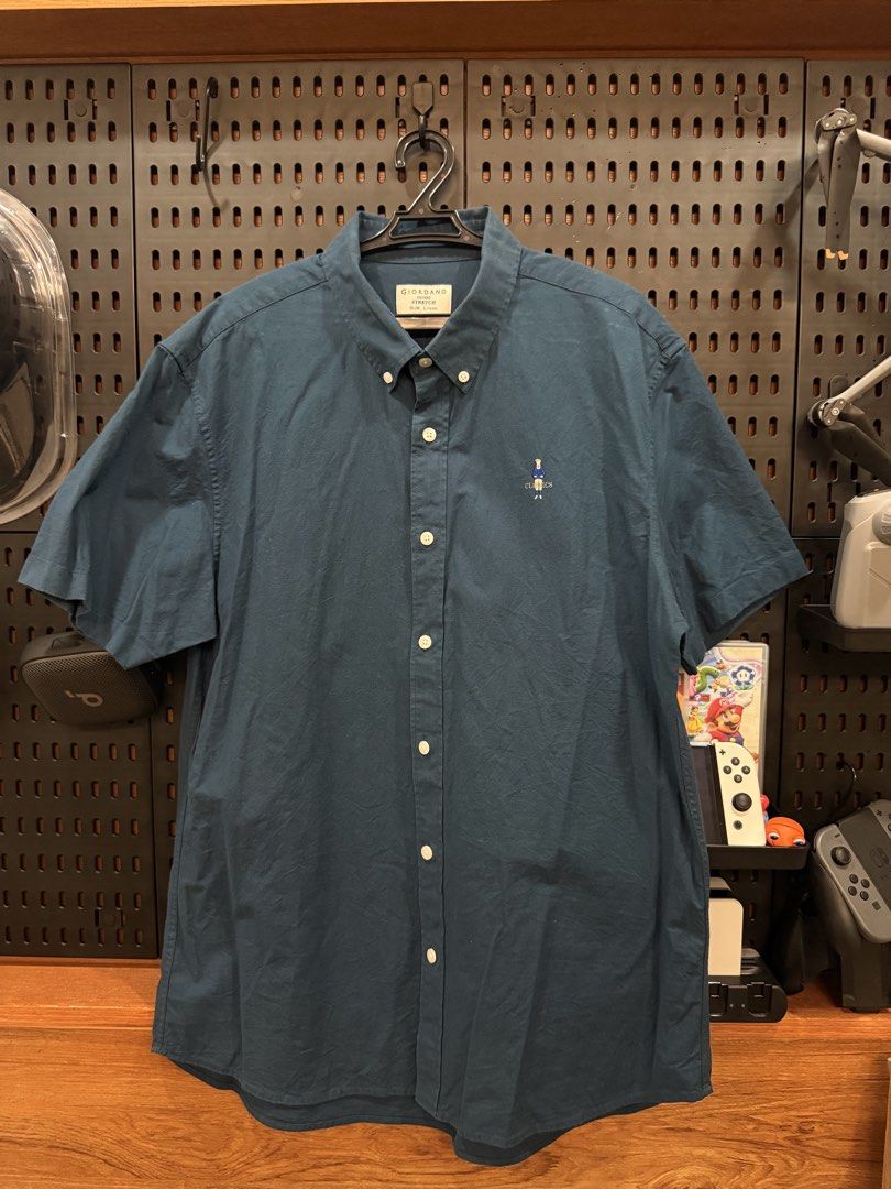GIORDANO Men's Short Sleeve Button Down Shirt (Category: Tshirts & Polo Shirts ) located in San Fernando. Submitted by archvst.selects (Listing ID 1463669100, Image 3). Description: - Dark blue short sleeve button down shirt - Brand: GIORDANO - Features a small embroidered bear graphic on the chest - Classic fit - Made with stretch fabric for comfort - Versatile for casual or smart casual wear - Button collar detail - Two pleats on the back for a