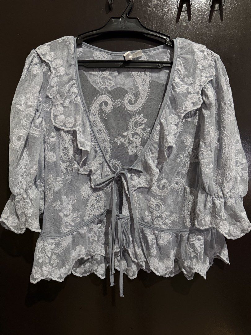 H&M Divided Embroidered Flounced Blouse (Category: Blouses) located in Iloilo. Submitted by ilo.preloved.ph (Listing ID 1463658806, Image 2). Description: - Light blue sheer lace blouse - Brand: H&M Divided - Intricate paisley embroidery all over - Ruffled neckline and hem - Tie front closure - Puff sleeves with ruffled cuffs - Size: Medium (M) - Perfect for layering over a bralette or cami - Color may vary due to lighting - No flaws - Never worn