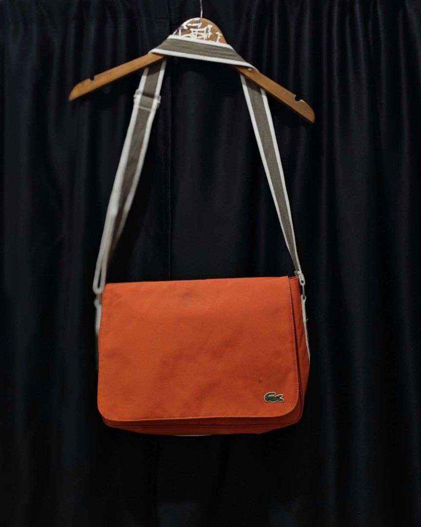 Lacoste Orange Messenger Bag (Category: Sling Bags) located in Baguio. Submitted by solo_ukay (Listing ID 1463694229, Image 1). Description: - Vibrant orange Lacoste messenger bag - Spacious main compartment with interior zip pocket - Front flap with secure velcro closure - Multiple internal pockets for organization - Adjustable strap for comfortable carrying - Ideal for everyday errands or travel adventures.