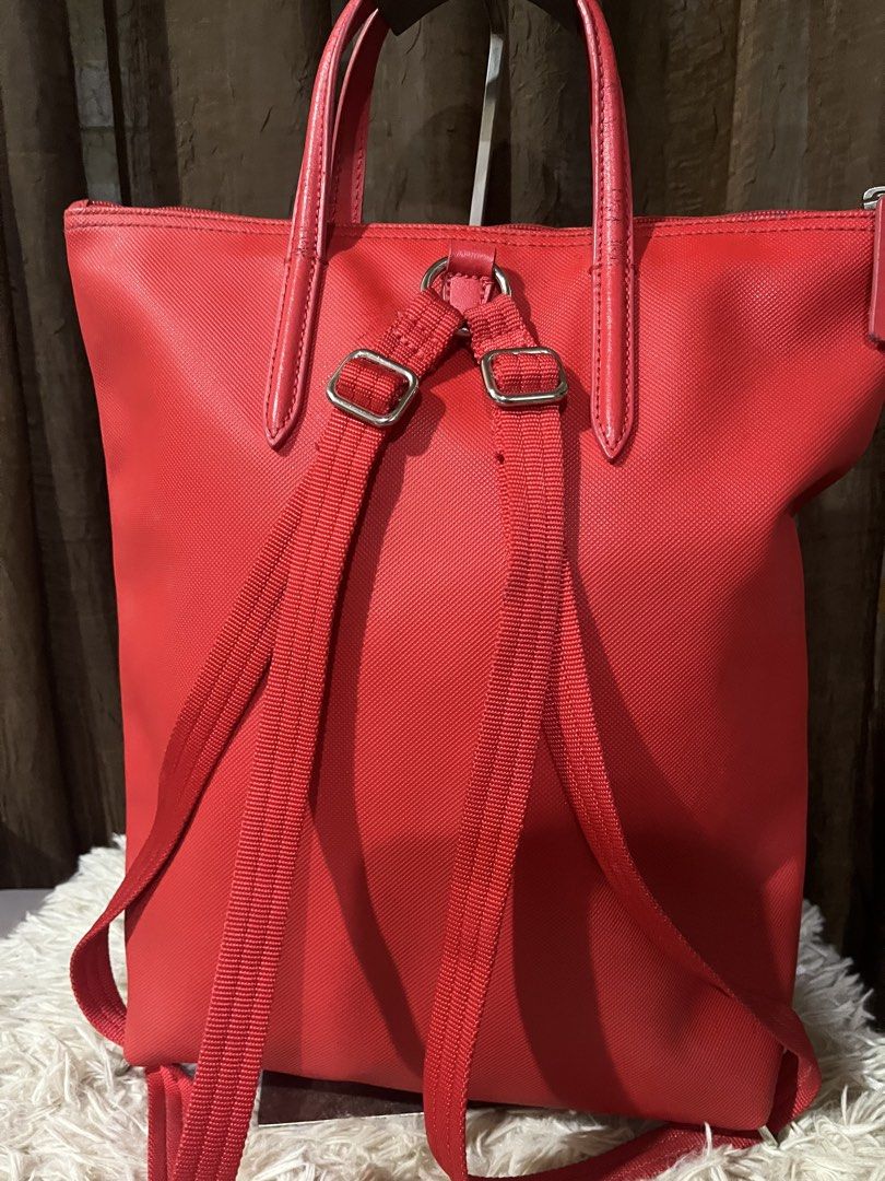 Lacoste Red Tote Bag Backpack (Category: Tote Bags) located in Davao. Submitted by loved.ones0606 (Listing ID 1463558698, Image 3). Description: - Red Lacoste tote bag - Can be worn as a backpack - Leather handles show some wearing and need wash - Zipper closure for security - Includes a small leather tag - Ideal for everyday use.