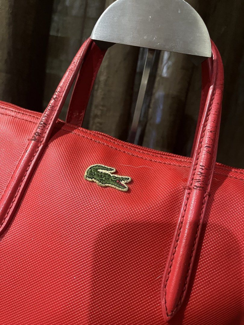 Lacoste Red Tote Bag Backpack (Category: Tote Bags) located in Davao. Submitted by loved.ones0606 (Listing ID 1463558698, Image 2). Description: - Red Lacoste tote bag - Can be worn as a backpack - Leather handles show some wearing and need wash - Zipper closure for security - Includes a small leather tag - Ideal for everyday use.