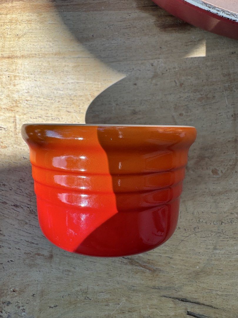 Le Creuset Stoneware Ramekin (Category: Cookware & Accessories) located in Naga. Submitted by ehloysah (Listing ID 1463589336, Image 1). Description: - Le Creuset stoneware pot - Vibrant orange and red glaze - Measures 4 inches tall - Light cream interior - Ideal for cooking or decorative display - Features Le Creuset branding and model number 0405 on the base.