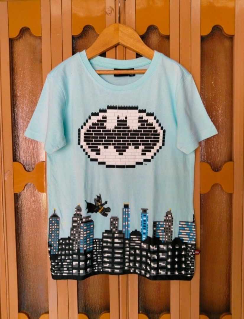 LEGO Batman T-shirt (Category: Babies & Kids Fashion) located in Pasig City. Submitted by babylove2003 (Listing ID 1463570220, Image 1). Description: Light blue t-shirt with a cool LEGO Batman graphic. Features a pixelated cityscape and Batman flying. Made by KABOOKI under license from The LEGO Group. Tag says size 140. Great for any young Batman fan who loves LEGO!.