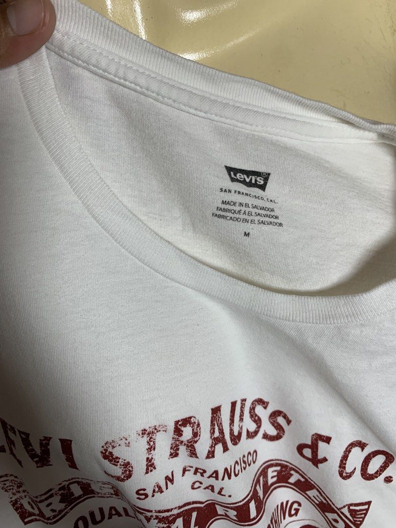 Levi Strauss & Co. White T-Shirt Size M (Category: Shirts) located in Davao. Submitted by cheineebau09680 (Listing ID 1463662695, Image 2). Description: - Classic white Levi's t-shirt - Features iconic red Levi Strauss & Co. graphic print - Made in El Salvador - Size: Medium (M) - Ideal for casual everyday wear - Pairs easily with jeans or shorts - A versatile wardrobe staple.