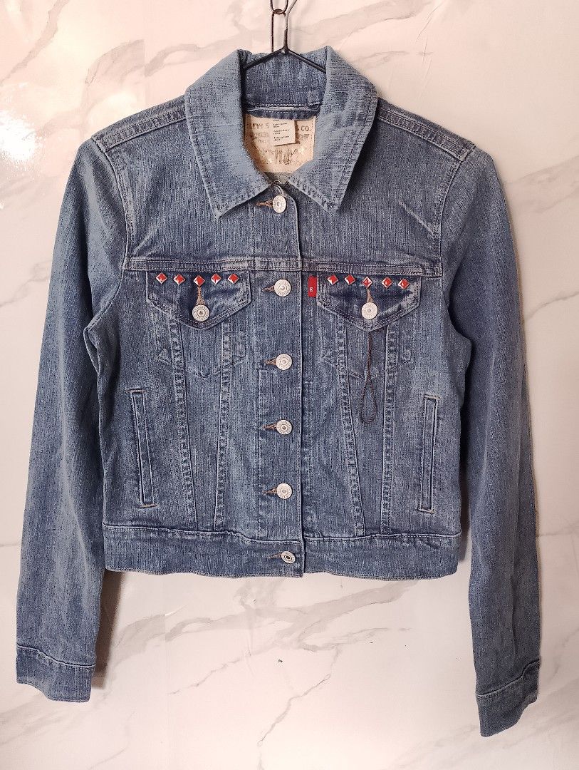 Levi's Denim Jacket with Red Studs (Category: Coats, Jackets and Outerwear) located in Manila. Submitted by jemarlubin04524 (Listing ID 1463573328, Image 1). Description: - Classic Levi's denim jacket - Unique red diamond stud embellishments on front chest pockets and back yoke - Button-up front with buttoned cuffs - Two chest pockets and two side pockets - Nice denim wash - Perfect for layering.