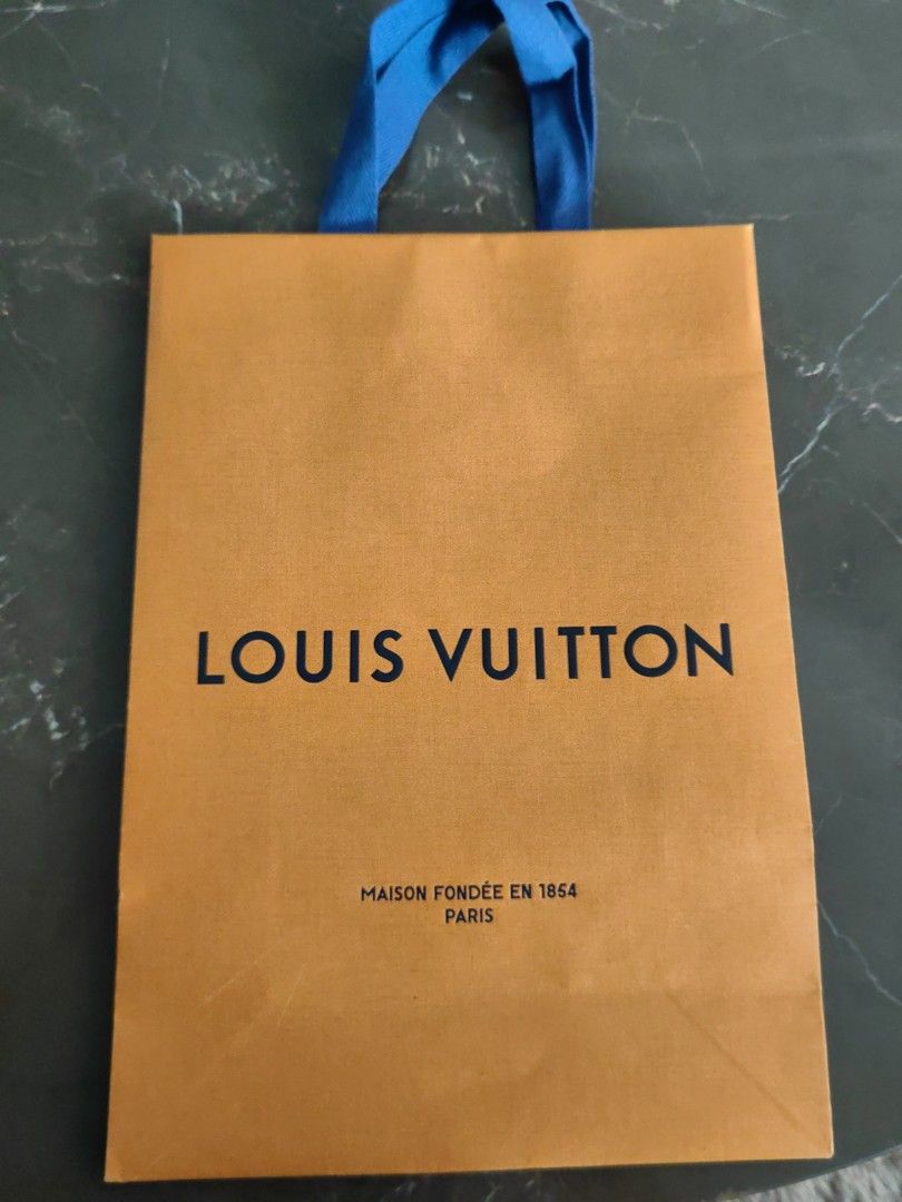 Louis Vuitton Shopping Bag (Category: Luxury Accessories) located in Makati City. Submitted by kruelscloset (Listing ID 1463603304, Image 1). Description: - Authentic Louis Vuitton paper shopping bag - Color: Orange with blue ribbon handles - "Maison Fondee En 1854 Paris" detail - Made in Vietnam - Approximate dimensions: 25cm (width) x 36cm (height) - Ideal for gifting or storing small items.