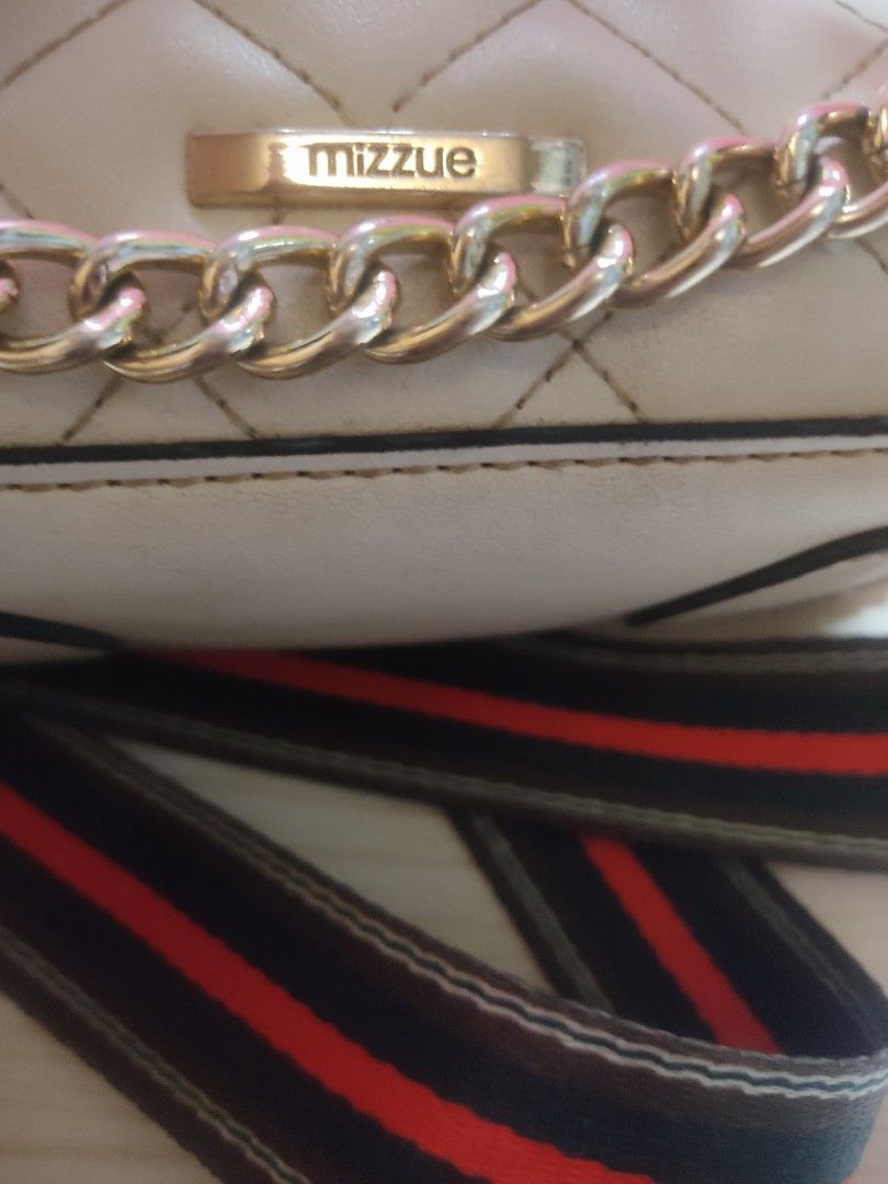 Mizzue Quilted Chain Crossbody Bag (Category: Cross-body Bags) located in Manila. Submitted by xiaochao.16 (Listing ID 1463739099, Image 3). Description: - Mizzue cream quilted crossbody bag - Features gold chain strap and separate striped fabric strap - Zipper closure on front and inside pocket - Shows some signs of wear on edges and interior - Perfect for everyday use.