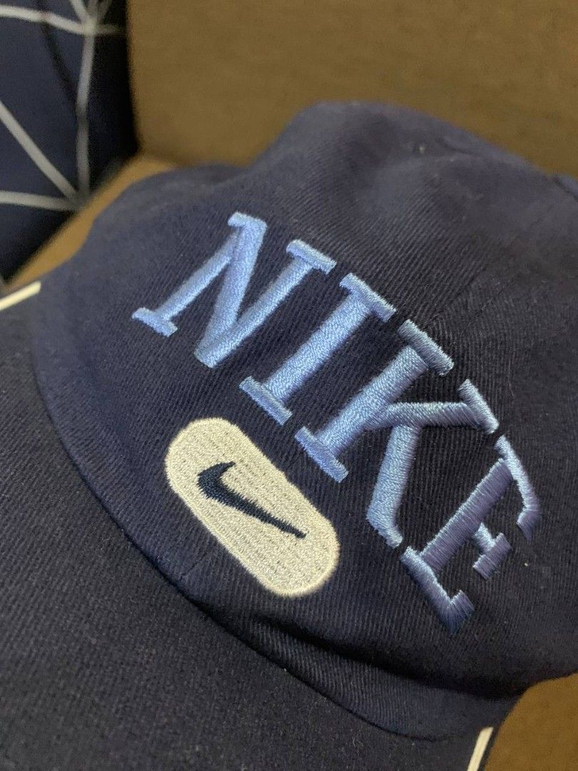 Navy Blue Nike Cap with White Trim (Category: Caps & Hats) located in Compostela. Submitted by francis_ace (Listing ID 1463663283, Image 2). Description: - Classic navy blue Nike cap - Embroidered 'NIKE' text and swoosh logo - White piping detail on brim - Adjustable strap for a custom fit - Ideal for everyday wear .