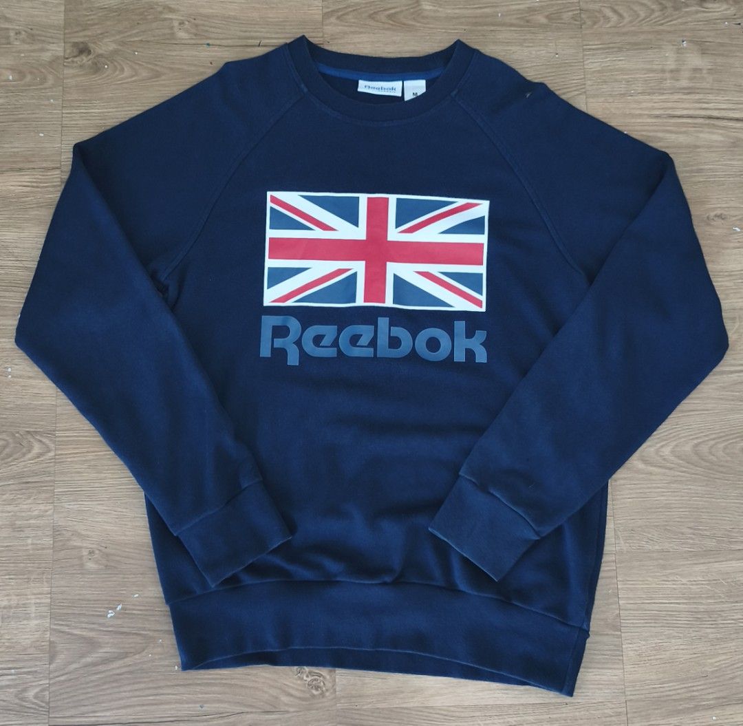 Navy Reebok Sweatshirt with Union Jack Graphic (Category: Coats, Jackets and Outerwear) located in Manila. Submitted by aye_posadas (Listing ID 1463681311, Image 1). Description: - Navy blue Reebok sweatshirt - Features a large Union Jack graphic on the front - Reebok logo below the graphic - Raglan sleeves for a comfortable fit - Ribbed cuffs and hem for a classic look - Ideal for casual wear and everyday styling.