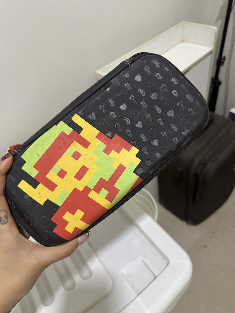 Nintendo Switch Case & Mario Stand accessories (Category: Nintendo) located in Mandaluyong City. Submitted by prelovedbytim (Listing ID 1463675990, Image 1). Description: - Space Invaders themed Nintendo Switch carrying case - Black with a cool pixelated alien design - Features an interior mesh pocket for accessories - Elastic straps to securely hold your Switch console and games - Comes with a bonus pink 3D printed Mario figure - Includes a matc