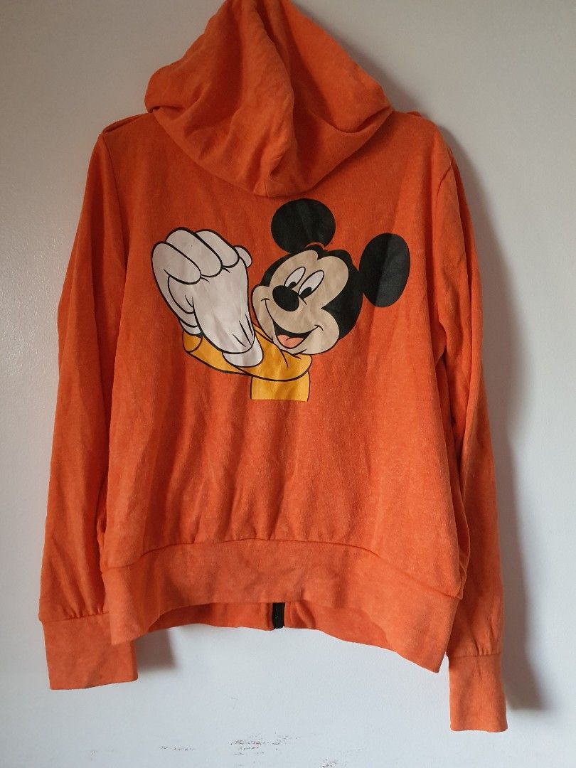 Orange Mickey Mouse Hoodie Jacket (Category: Coats, Jackets and Outerwear) located in Meycauayan. Submitted by shoptoown (Listing ID 1463569204, Image 2). Description: - Orange zip-up hoodie jacket - Features a cool Mickey Mouse graphic on the back - Two chest pockets with secure button closure - Long sleeves with comfortable ribbed cuffs - Made from soft fabric, ideal for everyday casual wear - Approximate measurement: 20 inches from pit to pit.