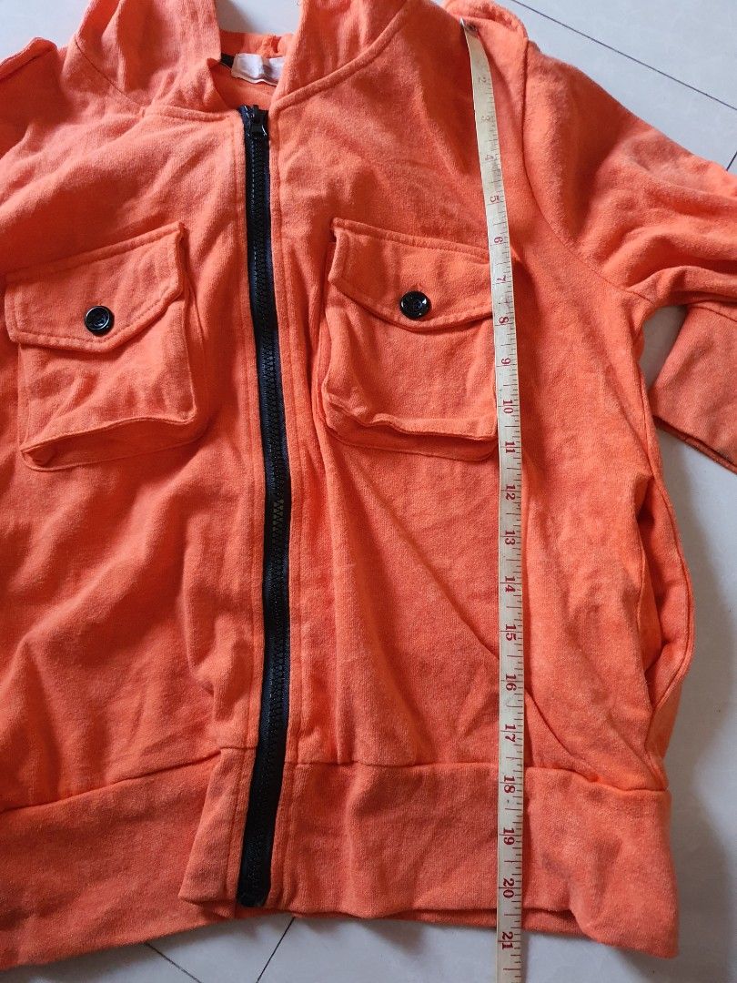 Orange Mickey Mouse Hoodie Jacket (Category: Coats, Jackets and Outerwear) located in Meycauayan. Submitted by shoptoown (Listing ID 1463569204, Image 3). Description: - Orange zip-up hoodie jacket - Features a cool Mickey Mouse graphic on the back - Two chest pockets with secure button closure - Long sleeves with comfortable ribbed cuffs - Made from soft fabric, ideal for everyday casual wear - Approximate measurement: 20 inches from pit to pit.