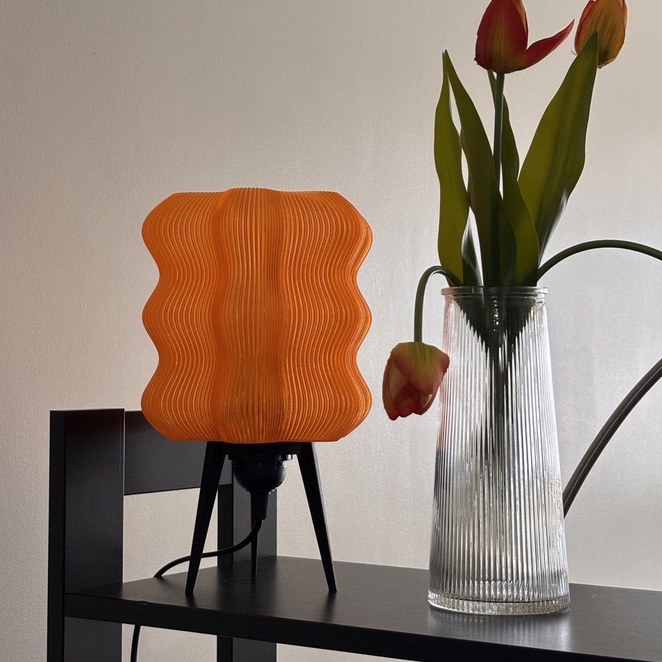 Orange Wavy Lamp (with Ikea LED bulb) (Category: Lighting) located in Mandaluyong City. Submitted by taag_ (Listing ID 1462878950, Image 3). Description: - Brand new, comes in a box and paper bag - Translucent orange - 18cm L x 18 cm W x 28 cm H - 3D printed, please allow minimal imperfections - Comes with an Ikea E27 Solhetta LED bulb (warm light) Licensed design by Eris https://makerworld.com/@eris2000.