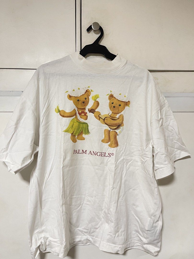 Palm Angels White T-Shirt - Dancing Bears (Category: Tshirts & Polo Shirts ) located in Paranaque City. Submitted by clubclassicz (Listing ID 1463692158, Image 1). Description: - Brand: Palm Angels - Size: Medium (M) - Material: 100% Cotton - Design: Features a fun Hawaiian-themed graphic of two bears - Logo: Palm Angels logo printed below the graphic - Chest: 23” - Length: 26” - Sleeves: 8 1/2” - Shoulders: 23”.