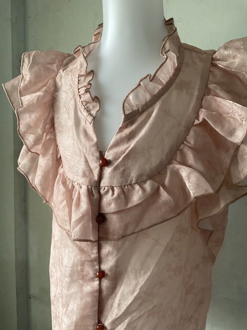 Pink Ruffled Blouse with Floral Pattern (Category: Blouses) located in Manila. Submitted by horangborahae (Listing ID 1463604127, Image 2). Description: - Light pink blouse - Delicate floral pattern - Ruffled neckline and sleeves - Button-up front with small brown buttons - Sleeveless - Fabric with a slight sheen - Perfect for a vintage-inspired look.