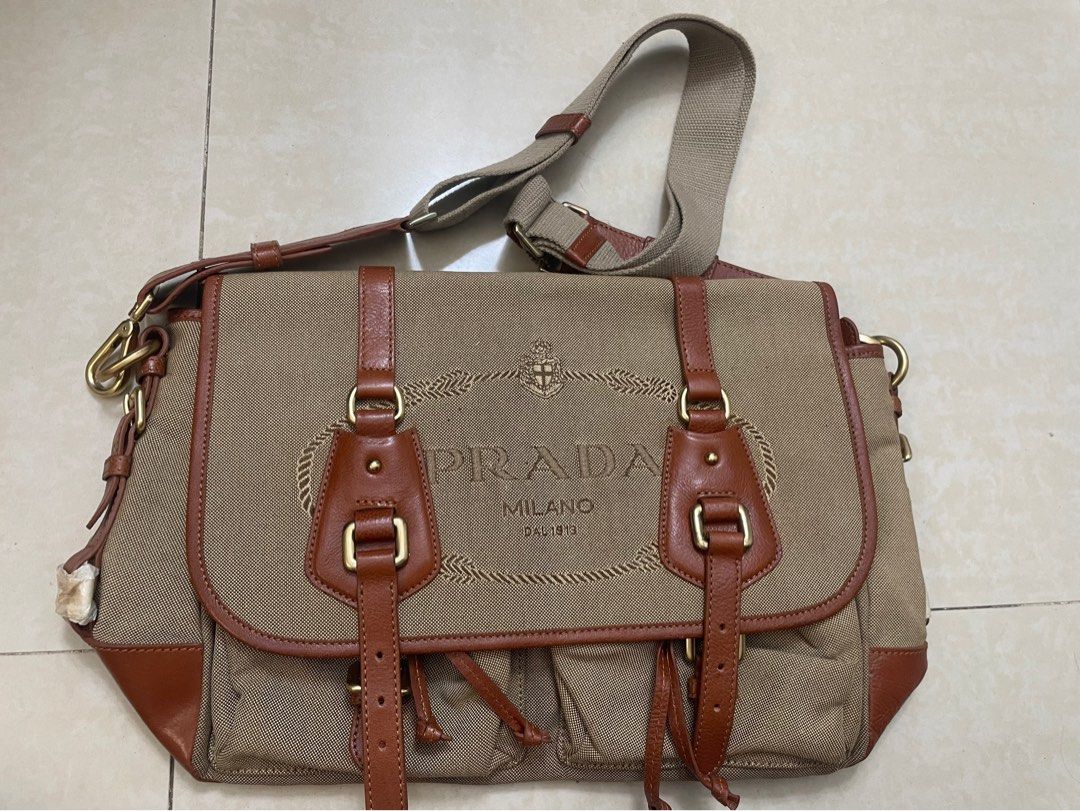 Prada Canvas Leather Shoulder Bag (Category: Luxury Bags & Wallets) located in Quezon City. Submitted by impulse.ph (Listing ID 1463664173, Image 1). Description: - Authentic Prada Bag - Color: Tan canvas with brown leather trim - Features: Adjustable shoulder strap, gold hardware - Interior: Zippered pockets and main compartment - Condition: Good, shows some signs of wear - Ideal for: Everyday use.