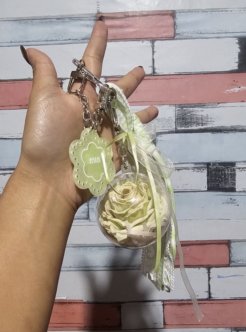 Preserved Rose bagchain with Flower Charm (Category: Charms) located in Baguio. Submitted by msgold2601 (Listing ID 1463740260, Image 1). Description: - Features a real preserved light yellow rose encased in a clear ball. - Adorned with a light green flower charm labeled 'Min'. - Includes decorative ribbons and a star charm. - Ideal for personalizing bags or keys. - A unique and charming accessory..