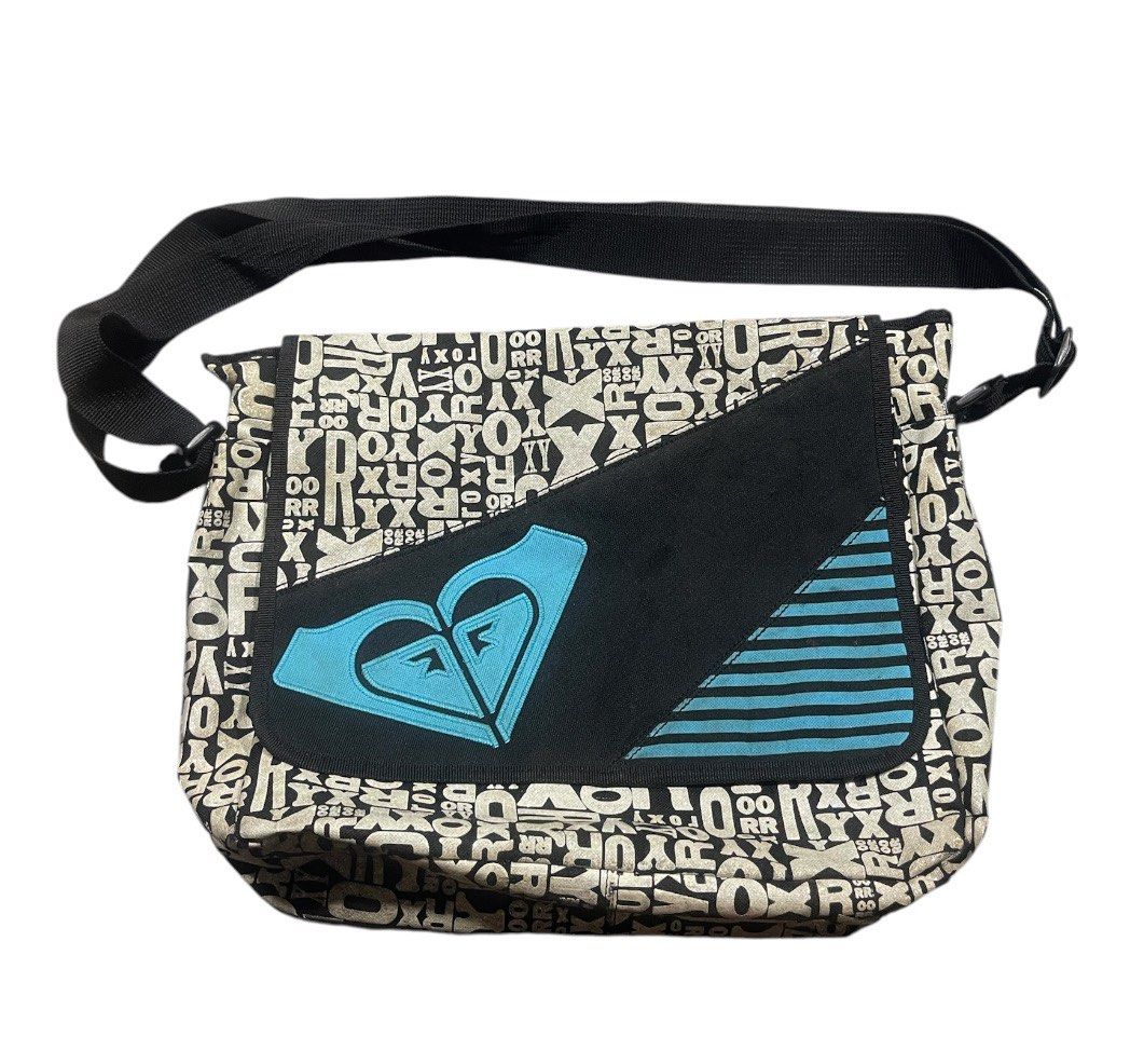Roxy Messenger Bag - All Over Logo Print Authentic (Category: Shoulder Bags) located in San Pedro. Submitted by lifebeginsaftercoff33 (Listing ID 1463662985, Image 2). Description: This is a vintage Y2K Roxy messenger bag featuring an all-over typographic logo print and a striking teal mountain logo on the front flap -Cool Roxy messenger bag - water resist - Black and white all-over logo print - Blue Roxy heart logo on front flap - Adjustable str