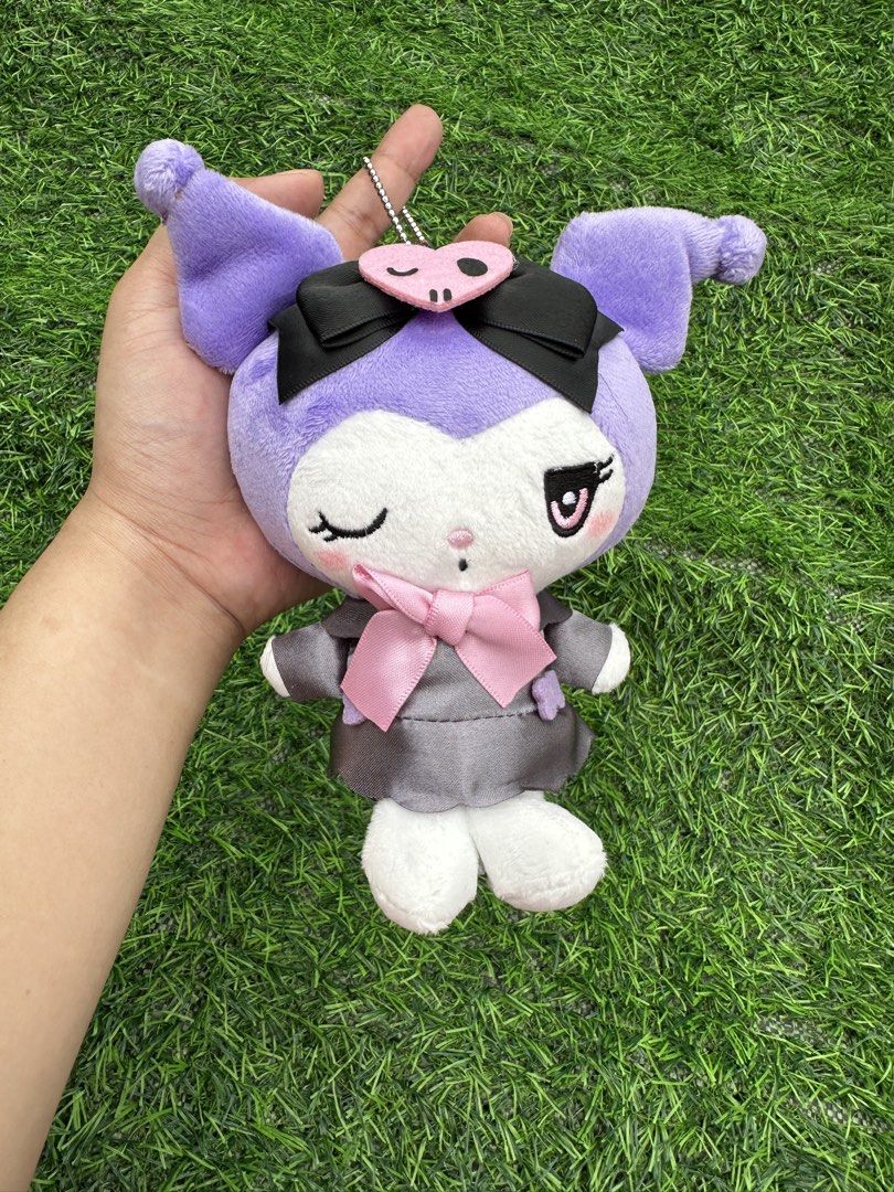 Sanrio Kuromi Plush Toy Keychain (Category: Plushies & Soft Toys) located in Manila. Submitted by ronoarabbit.ph (Listing ID 1463671215, Image 1). Description: - Winking Kuromi plush toy with a keychain attachment. - Features the cute purple character in a grey outfit. - Adorned with a pink bow and a black bow on its head with a pink heart accessory. - Ideal for decorating bags, backpacks, or as a fun collectible. - A must-have for any Sanrio fan