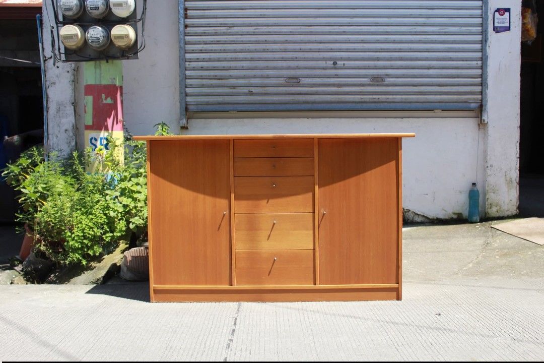 Sideboard Cabinet (Category: Shelves, Cabinets & Racks) located in Meycauayan. Submitted by marygracecasimiro (Listing ID 1463740868, Image 1). Description: Modern Wooden Sideboard Cabinet Five spacious drawers and two side cupboards with hinged doors. Finished in a warm honey-oak tone with sleek metallic knob pulls. Perfect for dining rooms, living rooms, entryways or additional home storage L:57 ¾ • W:19 • H:34 ¾ inches 11,500 pesos only💚 #hig