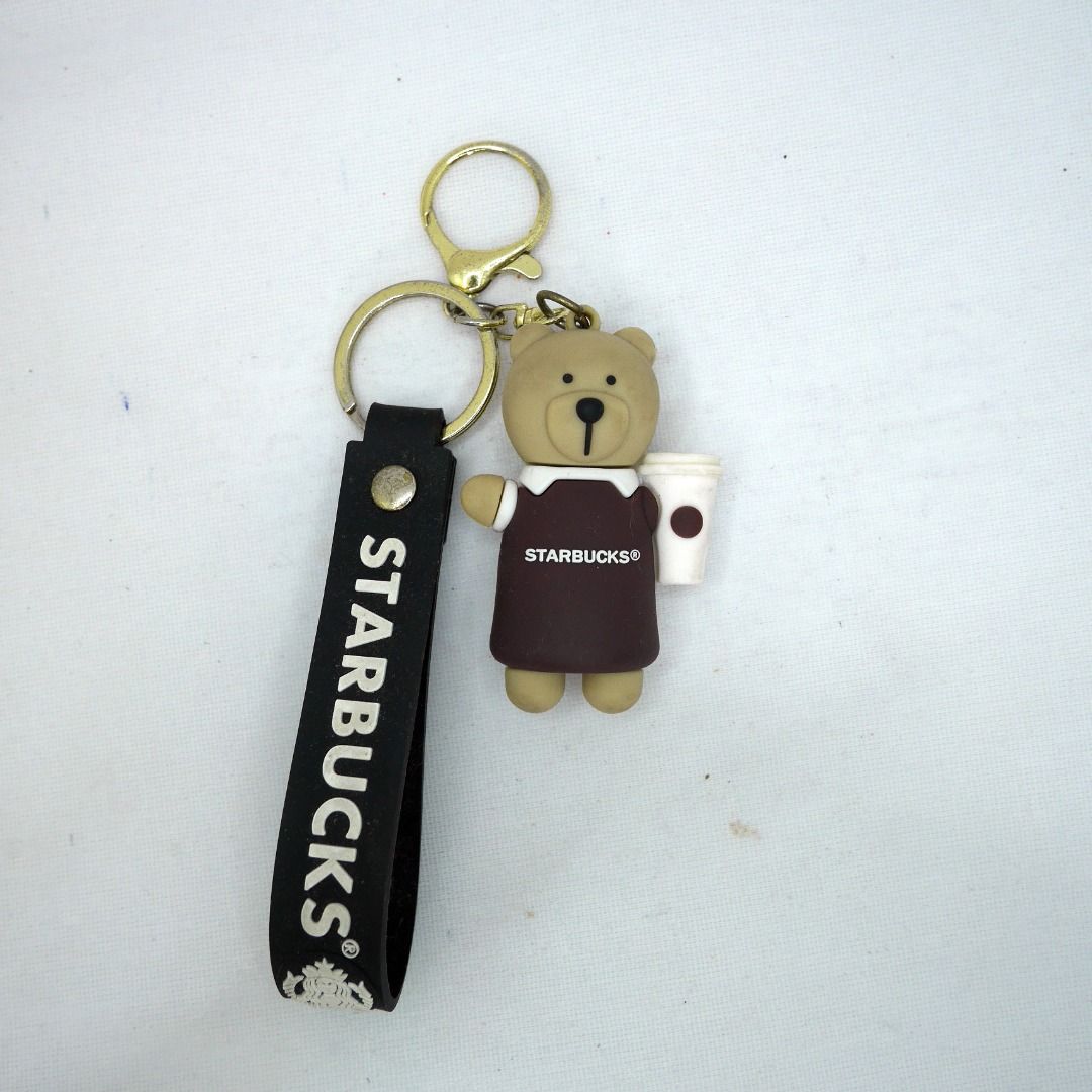 Starbucks Bear/bearista with Coffee Cup Keychain with hand strap (Category: Character Goods) located in Valenzuela. Submitted by cletini (Listing ID 1463701019, Image 1). Description: Cute Starbucks bear keychain holding a coffee cup, paired with a black Starbucks logo strap. Great for bags, keys or as a collectible accessory. ☕🐻 📌 Material: Rubber/PVC bear figure + metal hardware 📌 Includes key ring & lobster clasp 📌 Approx. 3–4" overall len
