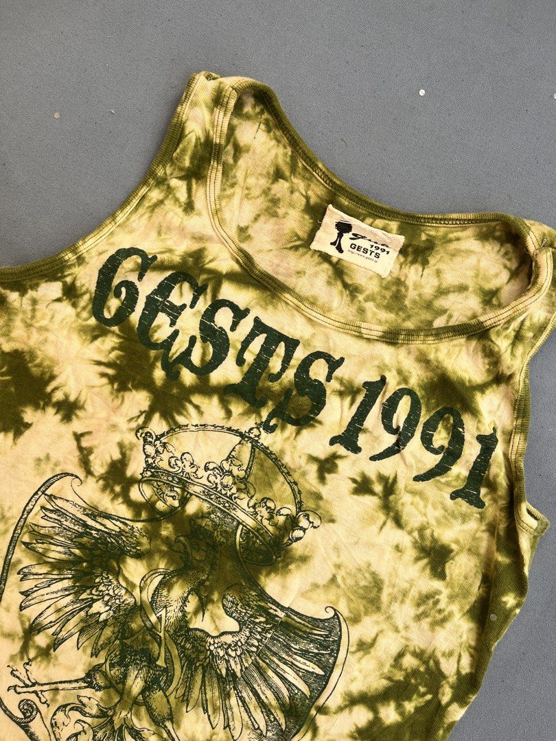Tie-dye graphic ribbed tank top (Category: Sleeveless) located in San Jose. Submitted by thymies (Listing ID 1463651232, Image 2). Description: Can fit small-med ‼️COLOR MAY VARY DUE TO LIGHTING‼️ Style: Fitted ribbed tank top / sleeveless tee Pattern & Color: Olive green and cream acid-wash / tie-dye effect Graphic: Crest coat of arms with a crowned eagle and gothic lettering (“GESTS 1991”) Aesthetic: Y2K Grunge / Alt / Vintage streetwear.