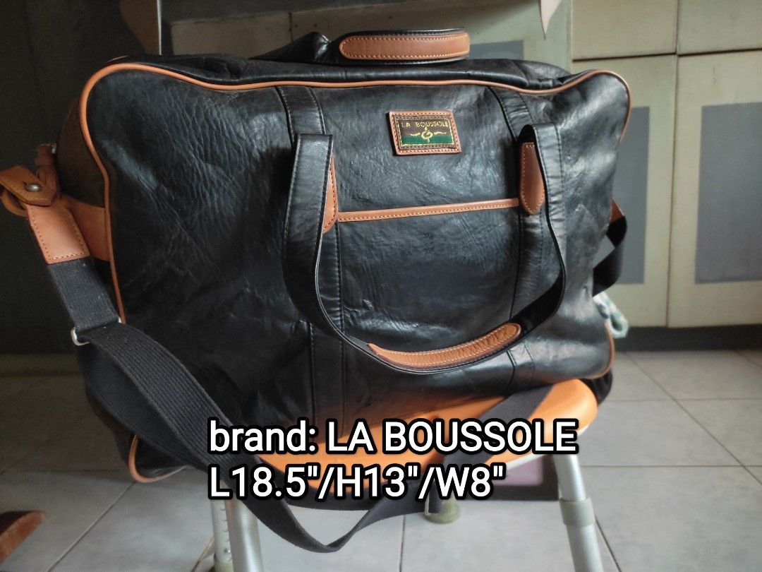 Travel bag (Category: Briefcases) located in Cainta. Submitted by allauthenticbymj (Listing ID 1463674600, Image 1). Description: The image shows a black-and-tan 2-way duffel bag by the brand La Boussole, listed with dimensions of 18.5" x 13" x 8" for ₱1,500. Brand: La Boussole Color: Black with tan lining accents Type: 2-way duffel bag Size: L18.5" / H13" / W8" Price: ₱1,500 Condition: Listed as having no issues Location: Cainta.